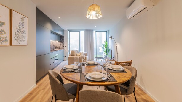 A modern dining area with a round wooden table set for four, surrounded by upholstered chairs. - RUAH F - Fantastic Flat by LovelyStay (Vila Nova de Gaia)