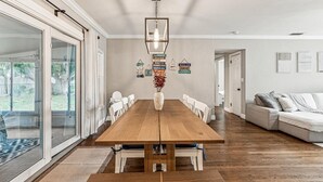 Un comedor amplio con una mesa y sillas de madera, una lámpara colgante y vistas al exterior a través de puertas de cristal correderas grandes.