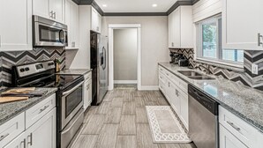Una cocina moderna con armarios blancos, un microondas, una estufa y un refrigerador.
