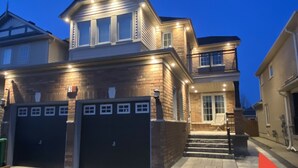 Ein zweistöckiges Haus mit Garage, Balkon und einer gut beleuchteten Eingangsparte.