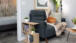 Ein modernes Wohnzimmer mit einem grauen Sofa, einem Holztisch, einem grauen Teppich und einem gerahmten Kunstwerk an der Wand.