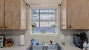 Eine Küche mit zwei Spülen, einem Fenster mit Blick und verschiedenen Küchenutensilien.