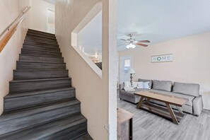 A staircase with dark steps leading to a landing, a ceiling fan, a sofa, and a coffee table in a living area. - Lovely 3-Bedroom (Killeen)