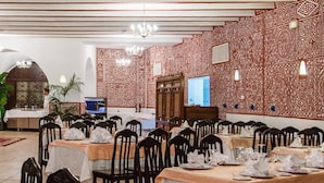 A banquet hall with tables set for a formal event, featuring a patterned wall and chandeliers. - Gourara Hotel  (Timimoun)