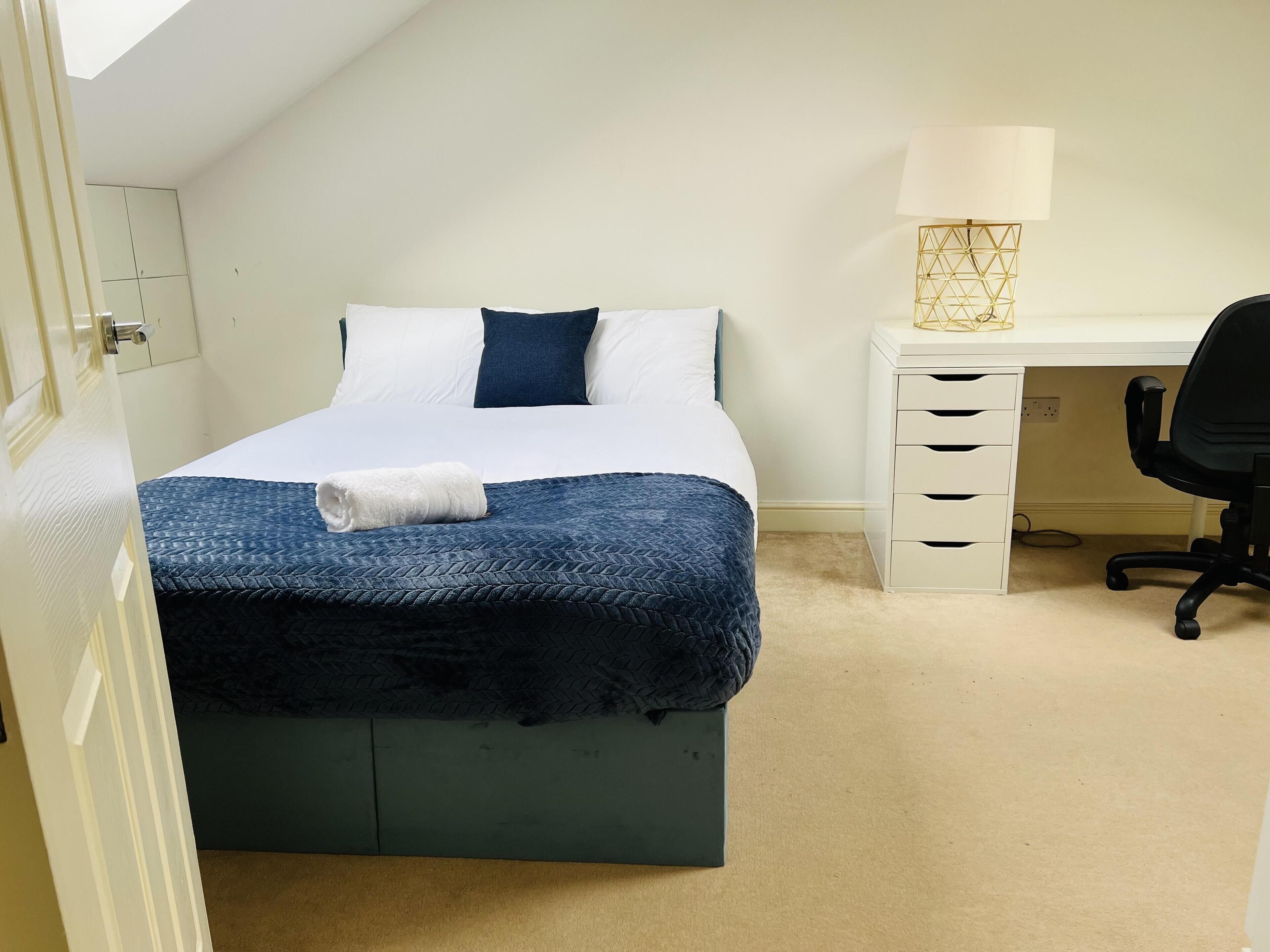 Ein ordentlich eingerichtetes Schlafzimmer mit Bett, Schreibtisch und Stuhl.