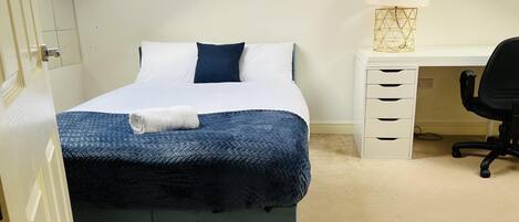 Ein ordentlich eingerichtetes Schlafzimmer mit Bett, Schreibtisch und Stuhl.