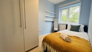 A bedroom with a bed, a wardrobe, a window, and a mirror. - Charming 3-bed House in Levenshulme, Manchester (Manchester)