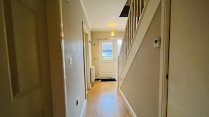 A narrow hallway with wooden flooring, white walls, and a door at the end. - Charming 3-bed House in Levenshulme, Manchester (Manchester)