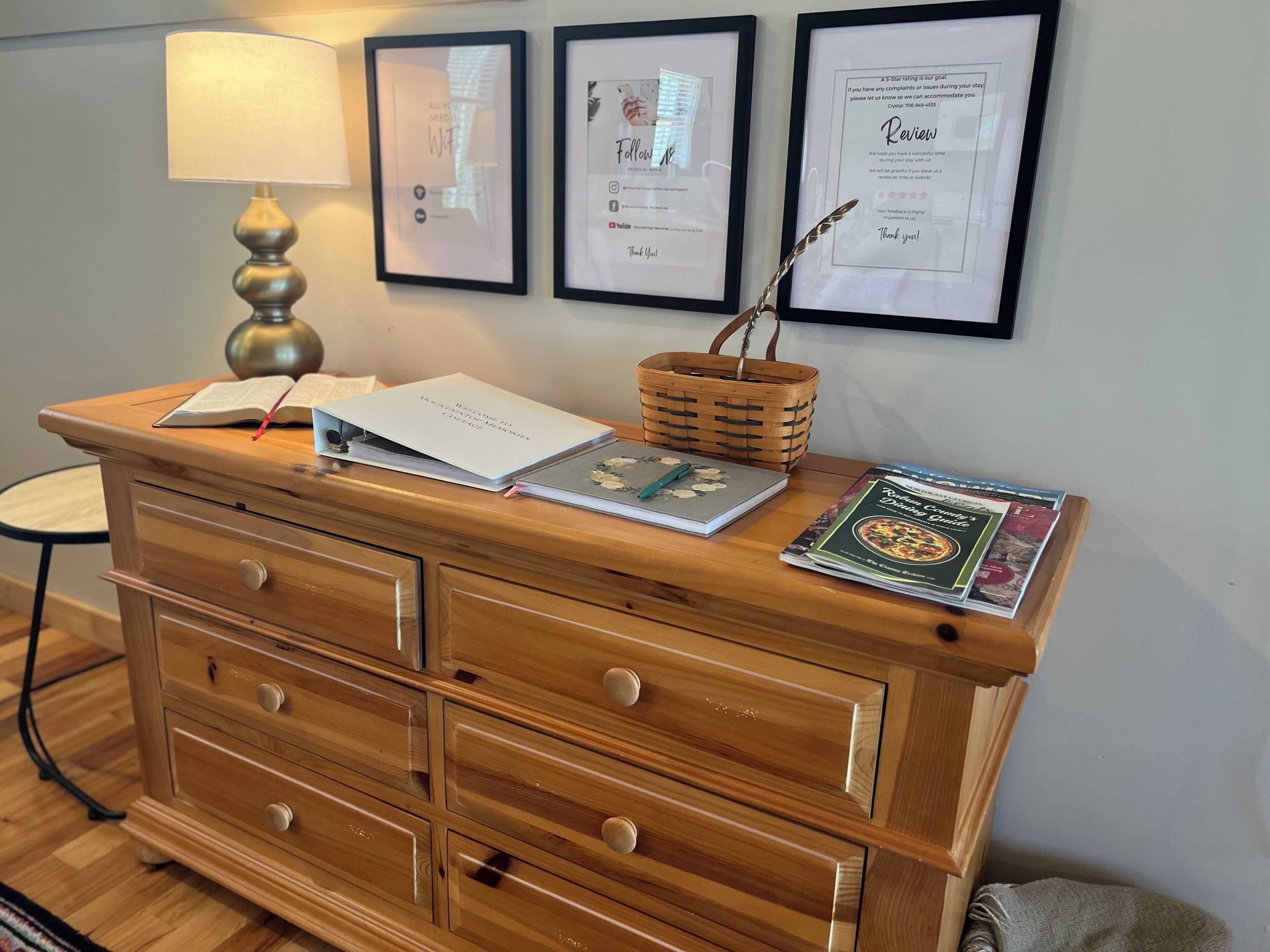 A wooden dresser with drawers, a lamp, a basket, and a few books.
