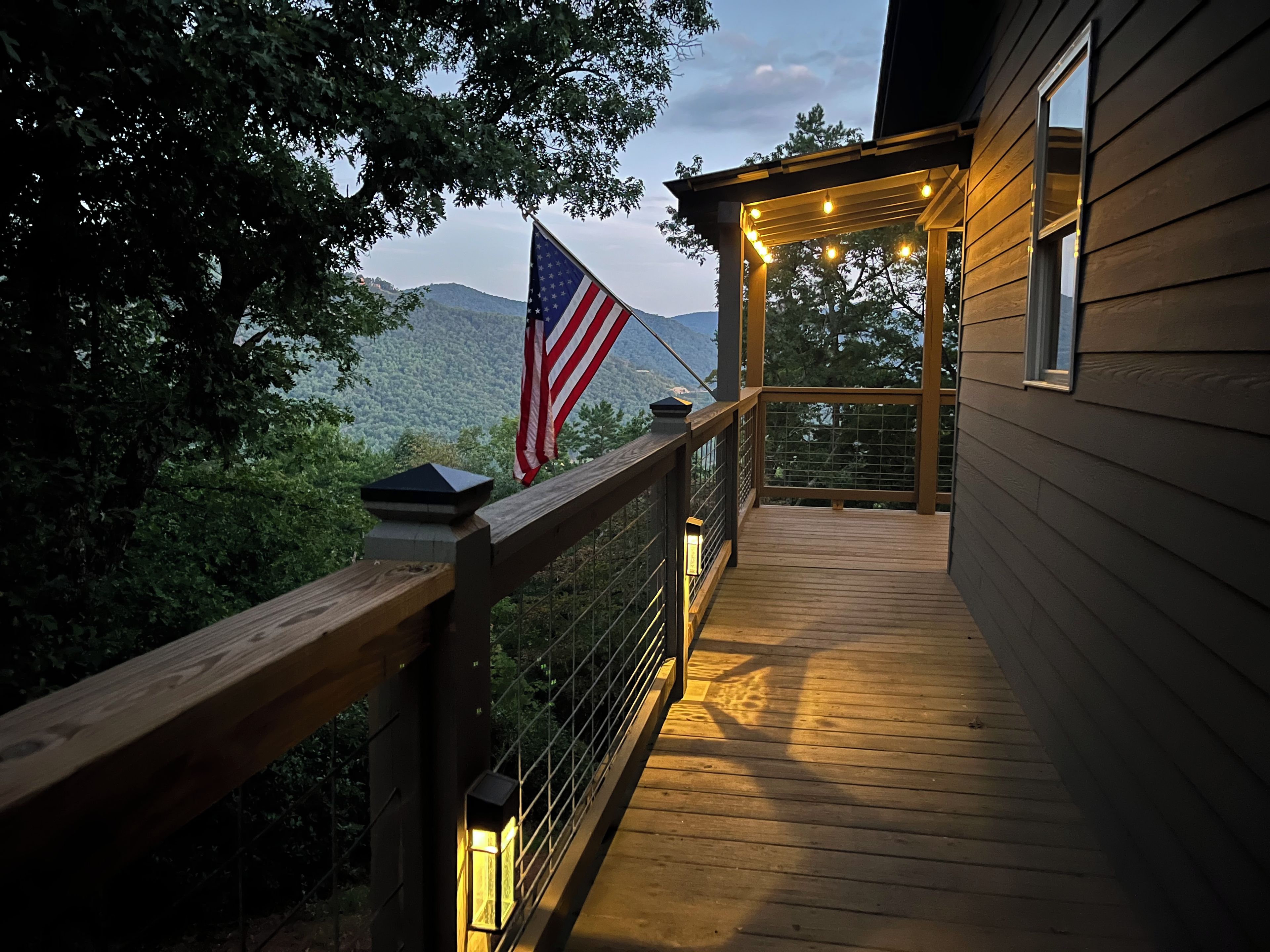 A wooden deck with a railing, an American flag, and a lantern.