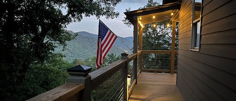 A wooden deck with a railing, an American flag, and a lantern.
