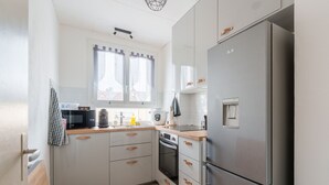 A compact kitchen with white cabinets, a stainless steel refrigerator, a microwave, and a stove.
