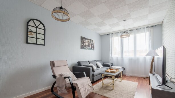 A modern living room with a sofa, a rocking chair, a coffee table, and a television.