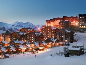 Une station de montagne enneigée, avec des bâtiments en bois et un télésiège.