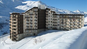 Un hôtel à plusieurs étages, doté de balcons, qui se dresse sur fond de montagnes enneigées.