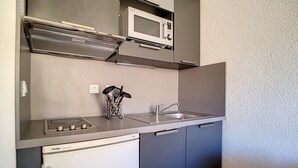 Une cuisine compacte équipée d’un four à micro-ondes, d’une cuisinière, d’un évier et d’un lave-vaisselle.