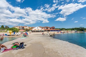 Una playa con piscina, sombrillas y sillas de playa.