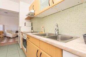 Cocina compacta con un lavamanos doble, un microondas, una estufa y un armario con microondas encima.