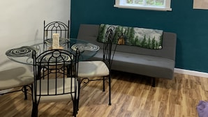Ein Essbereich mit einem Glastisch, schwarzen Metallstühlen und einer wandfarbenen Teal-Wand.