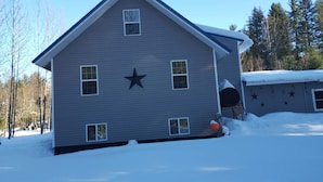 Ein zweigeschossiges Haus mit Sternenverzierung an der Vorderseite, umgeben von Schnee.