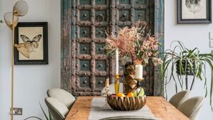 A dining area with a wooden table, chairs, a decorative bowl, and a hanging light fixture. - Beautifully Curated 4 Bed Family Home w/ Garden (London)