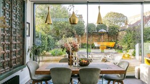 A dining area with a large table, four chairs, and hanging pendant lights. - Beautifully Curated 4 Bed Family Home w/ Garden (London)