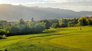 A golf course with a flagstick, surrounded by trees and mountains in the background. - Discover Year-Round Adventure at MH511 | Juniper Hollow Retreat in Eden, UT! (Eden)