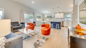 A modern living room with a grey sofa, orange armchairs, a coffee table, and a kitchen in the background. - Boise Retreat ~ 2 Mi to Boise State University! (Boise)