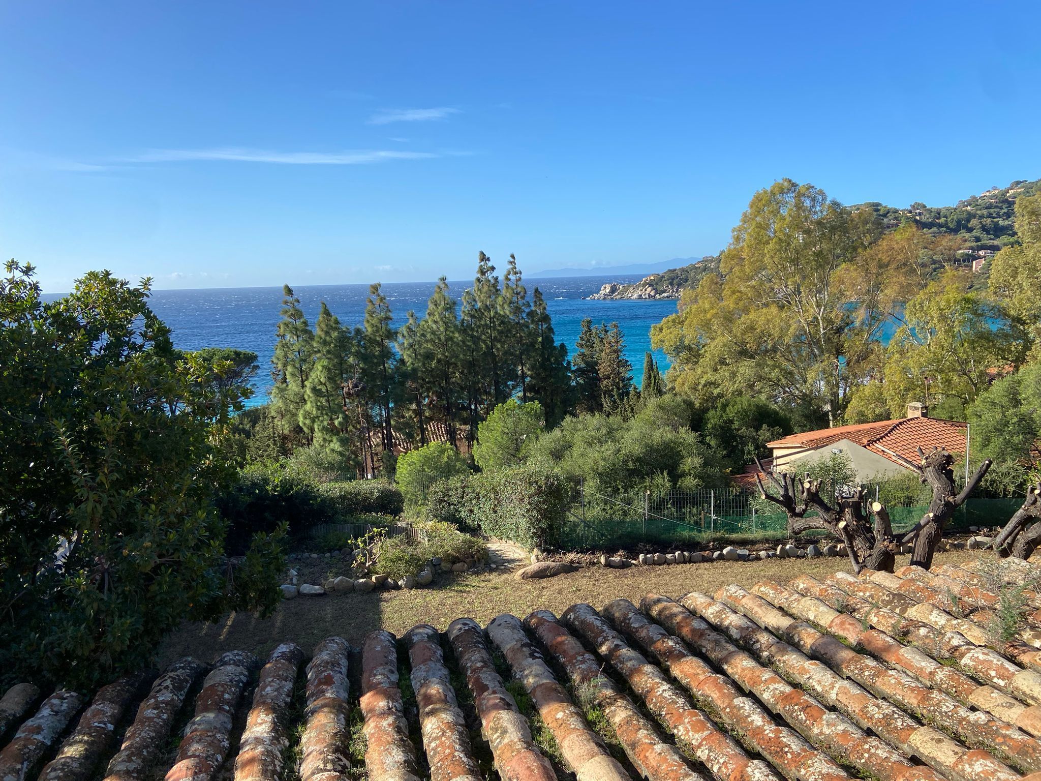 Una propiedad costera con tejas de terracota, vistas al mar y vegetación circundante.