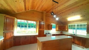 A spacious kitchen with wooden cabinets, a large island, and ample natural light from windows. - Presidential Suite Cottage 10 (Pointe Michel)