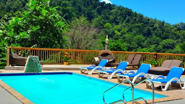 A swimming pool with blue tiles, surrounded by lounge chairs and a wooden deck. - Presidential Suite Cottage 10 (Pointe Michel)