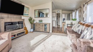 Ein geräumiger Wohnbereich mit Flachbildfernseher, einer Holzunterhaltungseinheit und einem gemütlichen Sofa.