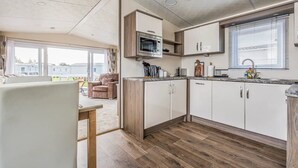 Eine moderne Küche mit weißen Schränken, einer Mikrowelle und einem Fenster mit Jalousien.