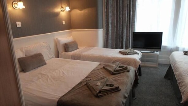 Ein Hotelzimmer mit zwei Betten, einem Fernseher und einem Schreibtisch.