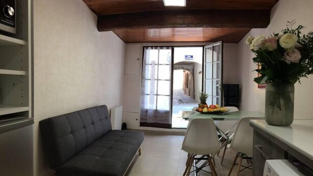 A compact living space with a sofa, a dining table with chairs, a kitchen area, and a view through a glass door. - Art, Sailing, Fishing, Beach ... Sérignan! (Sérignan)