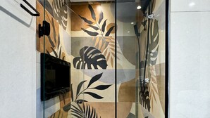 A modern shower enclosure with a glass door, a mounted TV, and a rain showerhead. - Studio Vila Nova (São Paulo)