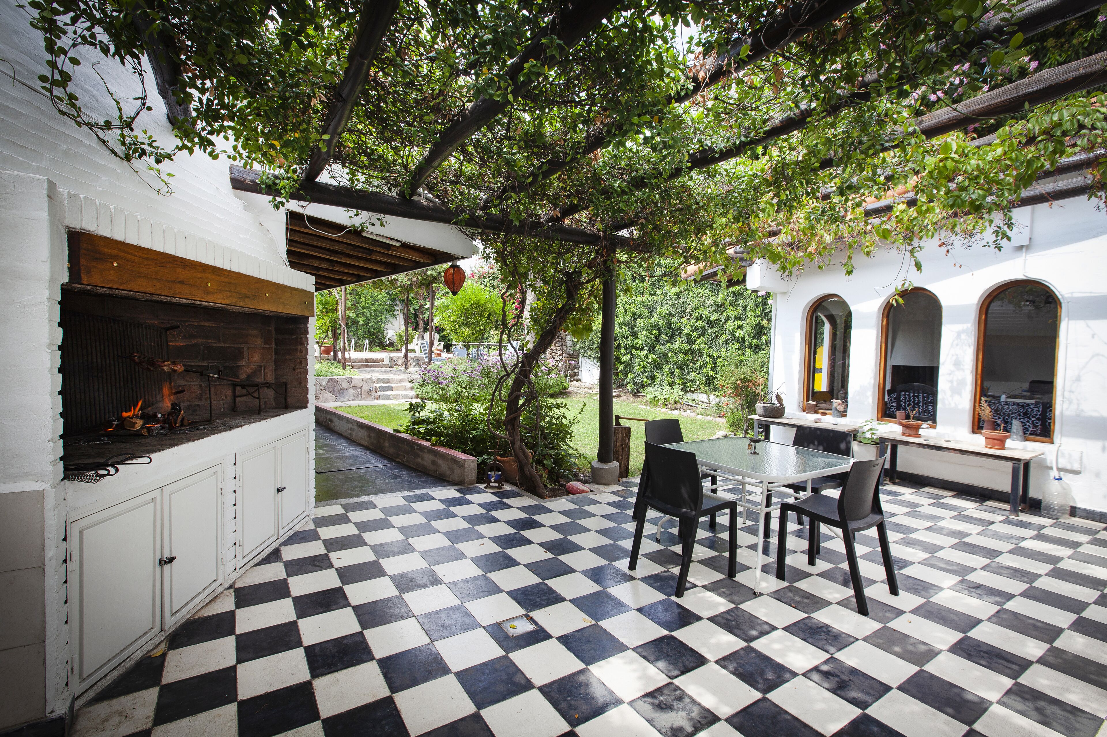 A patio with a checkered floor, a grill, and a table with chairs.