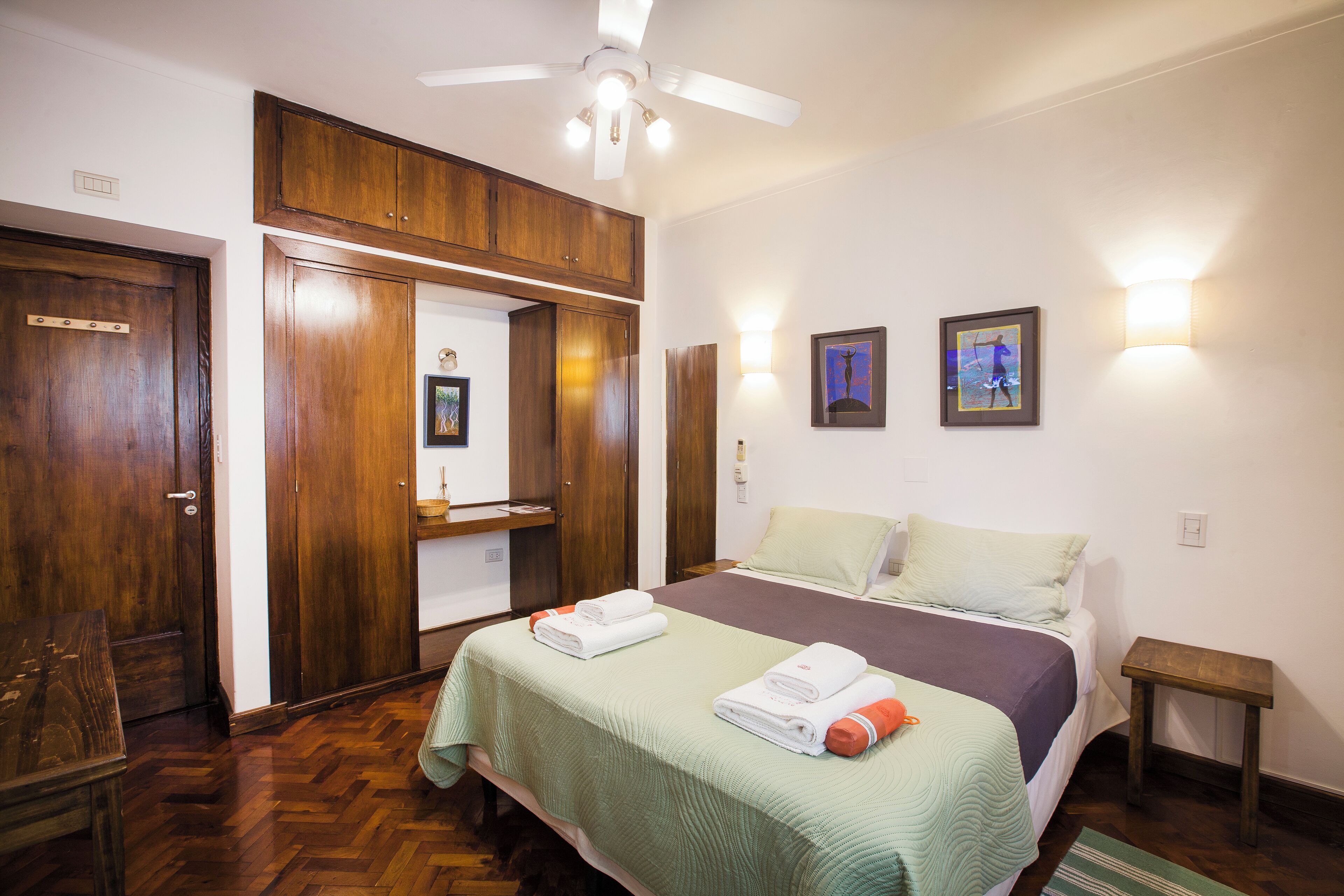 Une chambre d’hôtel avec un lit, une armoire en bois et une petite table.