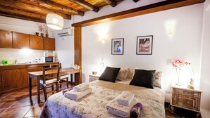 Une chambre à coucher comprenant un lit, des tables de chevet, un bureau et un coin cuisine.