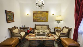 A traditional living room with a chandelier, two sofas, a coffee table, and a red curtain.