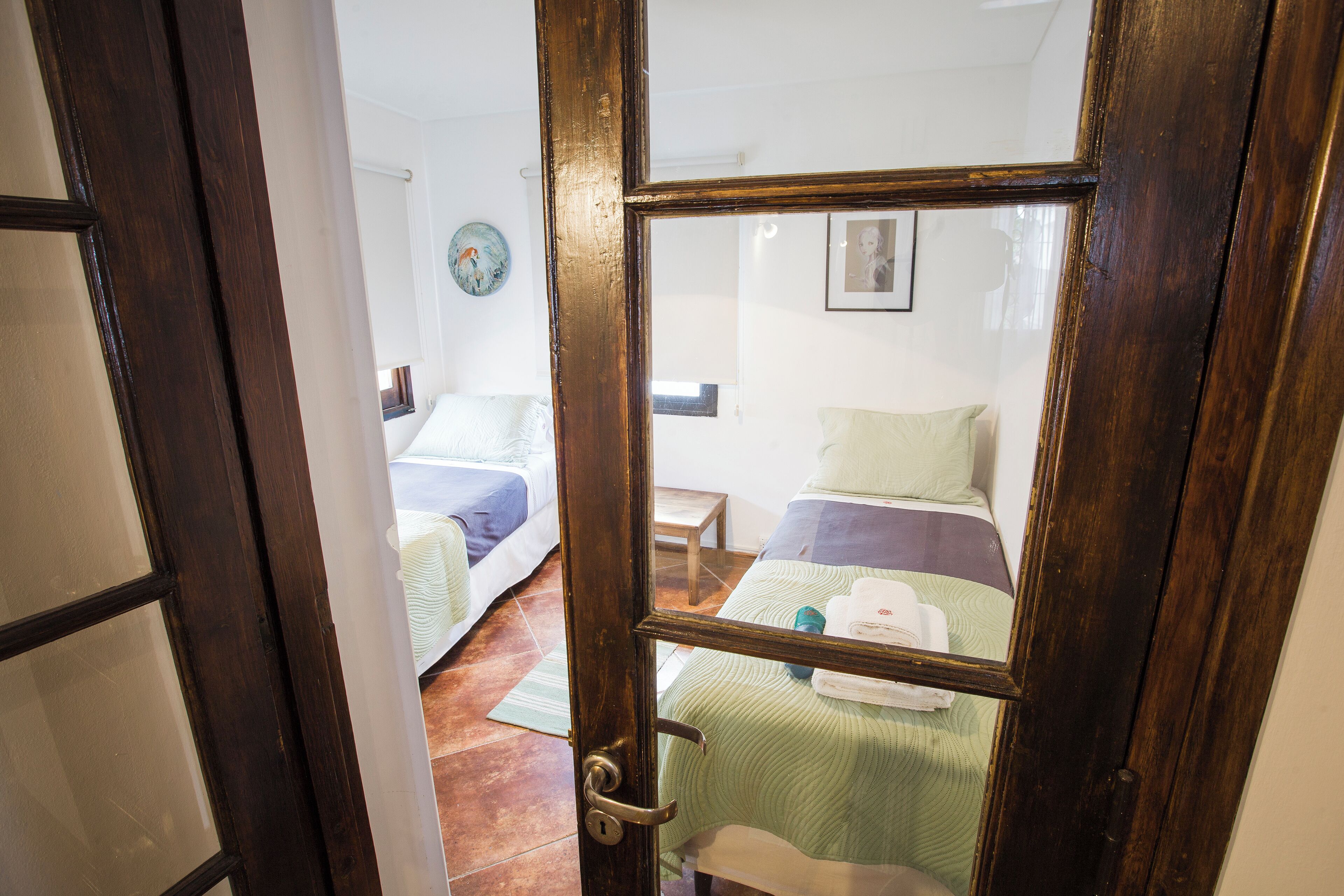 Een kamer met twee bedden, een houten deur en een klein tafeltje.