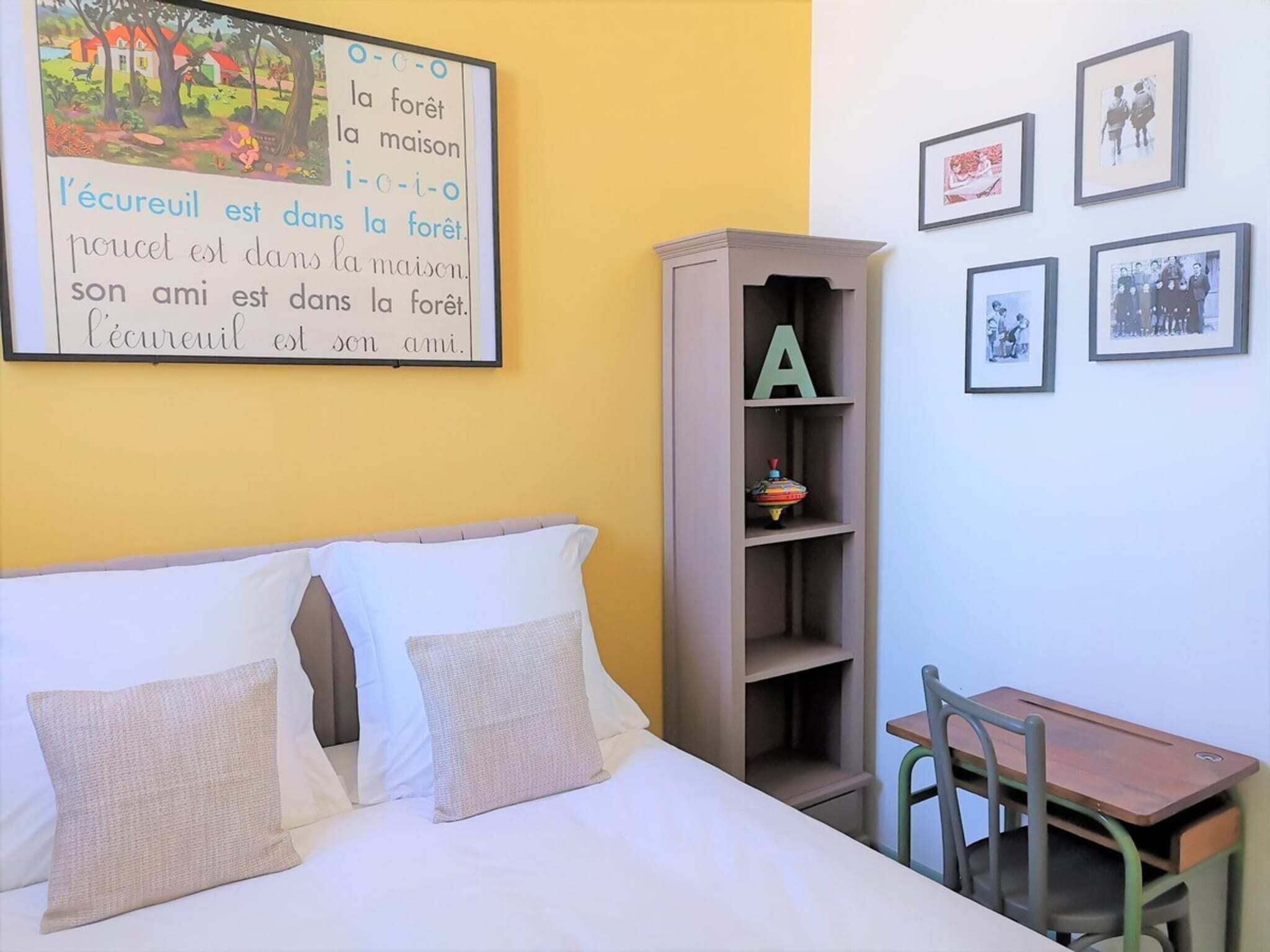 A bedroom with a bed, pillows, a desk, and a bookshelf.