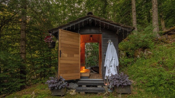 A wooden cabin with an open door, a bench outside, and a towel hanging on the door. - Le Petit Rêve - Lac de Montriond (Montriond)