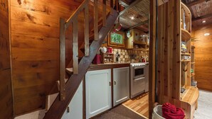 A wooden interior with a staircase leading to a kitchen area. - Le Petit Rêve - Lac de Montriond (Montriond)