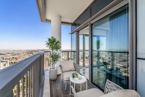 A balcony with a view of the city, furnished with a chair, a small table, and a potted plant. - Spectacular View of the old city in Jerusalem (Jerusalem)
