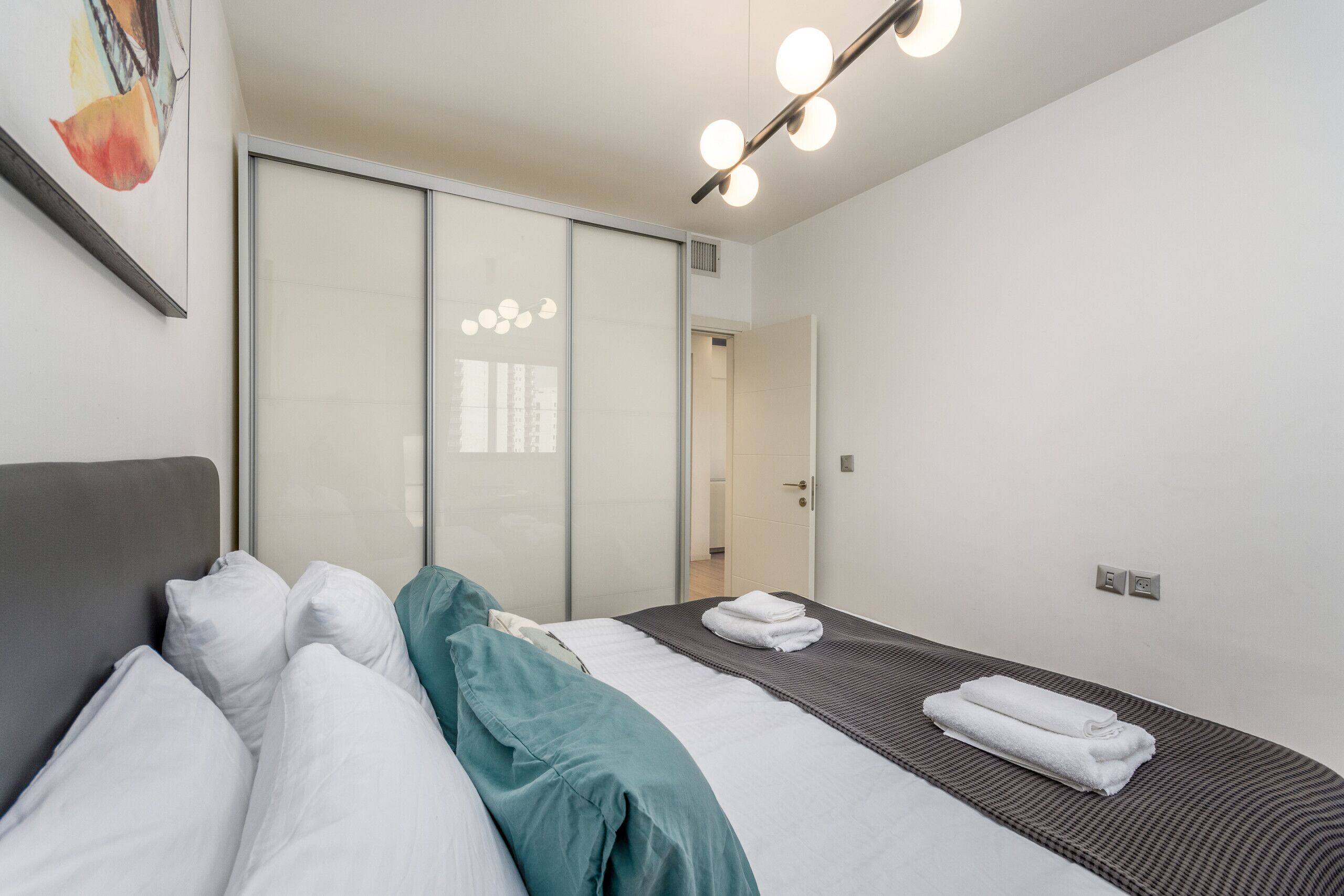 A hotel room with a bed, a large mirror, and a ceiling light fixture.