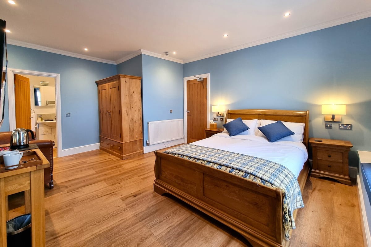 A bedroom with a wooden bed, a nightstand, a dresser, and a radiator.