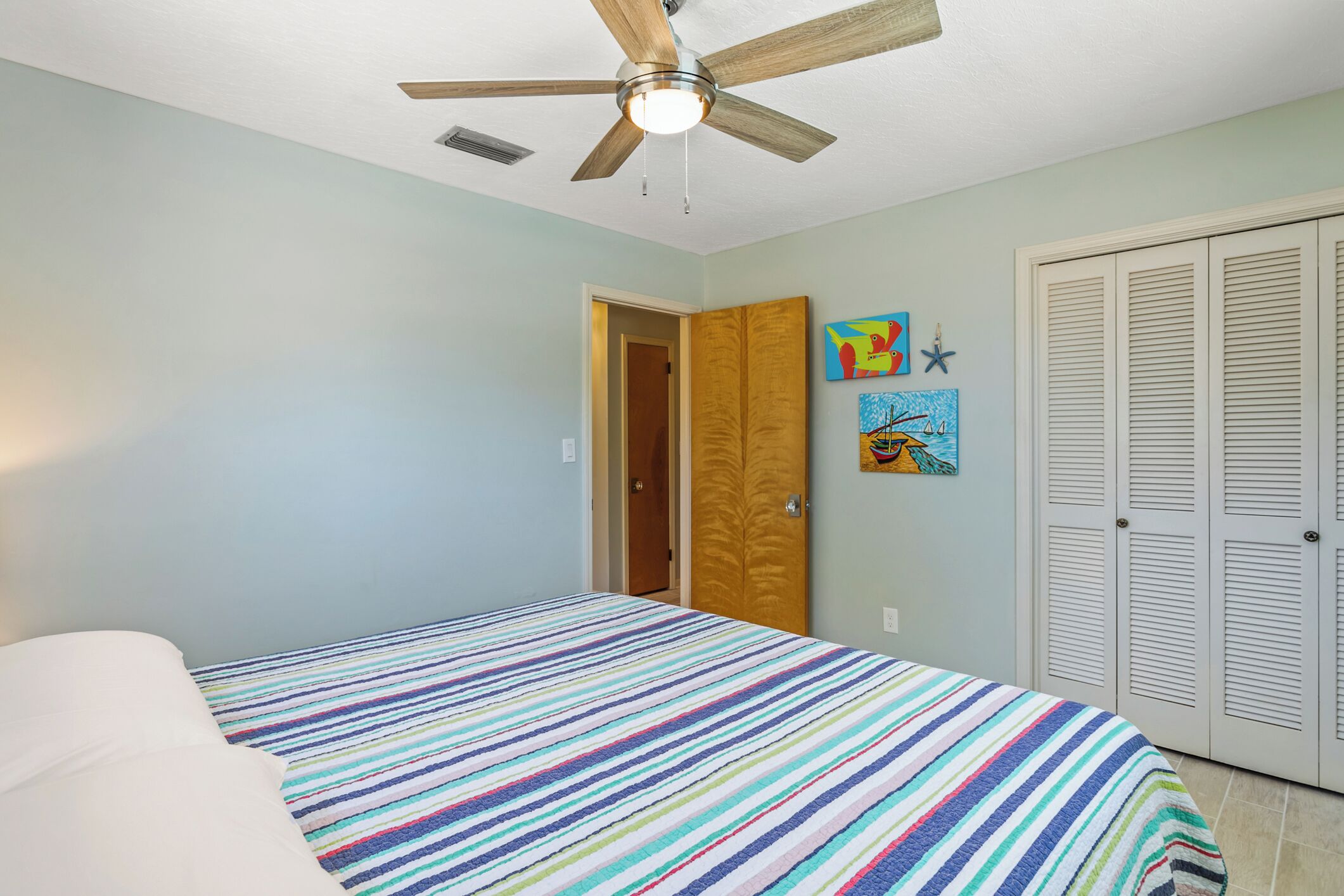 Ein Schlafzimmer mit Bett, Deckenventilator, Tür und Schrank.