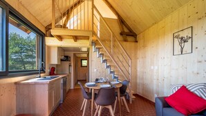 Een houten interieur met een eethoek, een trap en een bank met een rood kussen.