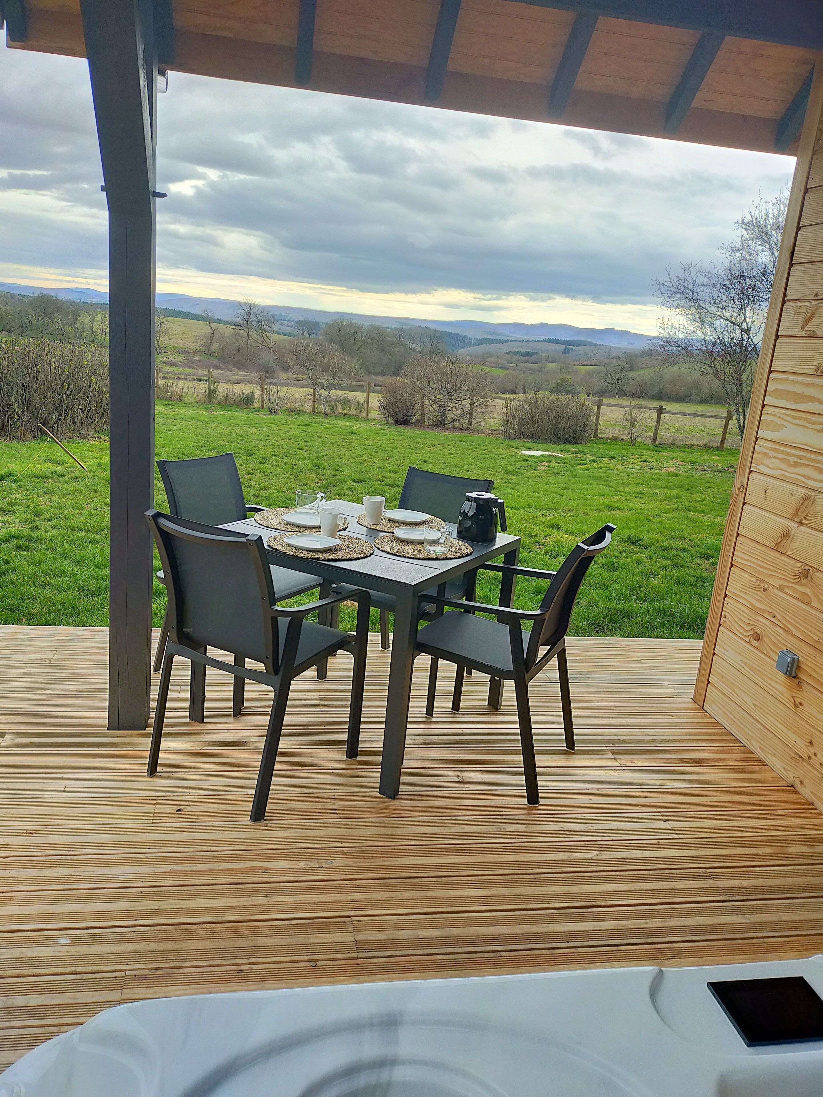 Un espacio de comedor al aire libre cubierto, con una mesa preparada para dos, con vistas a un paisaje con césped.